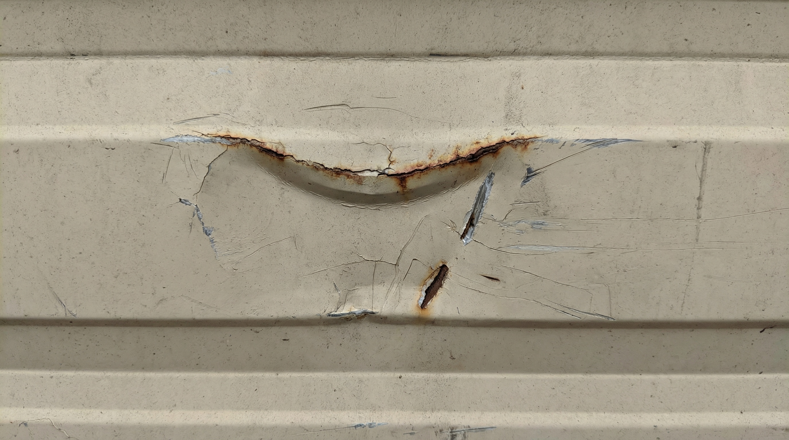 close-up of dented garage door panel showing impact damage