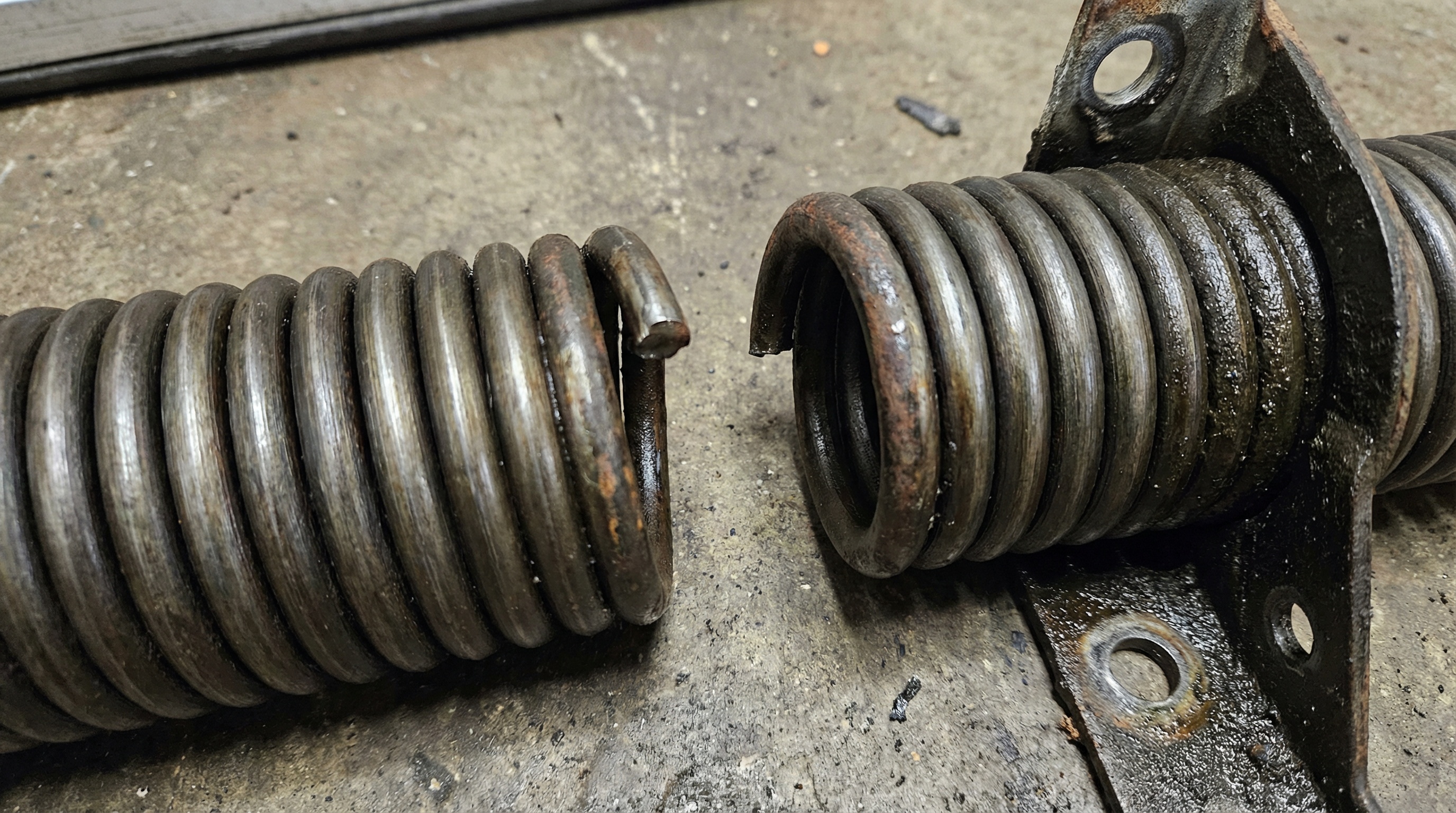 Close-up of a broken garage door torsion spring showing visible gap and wear