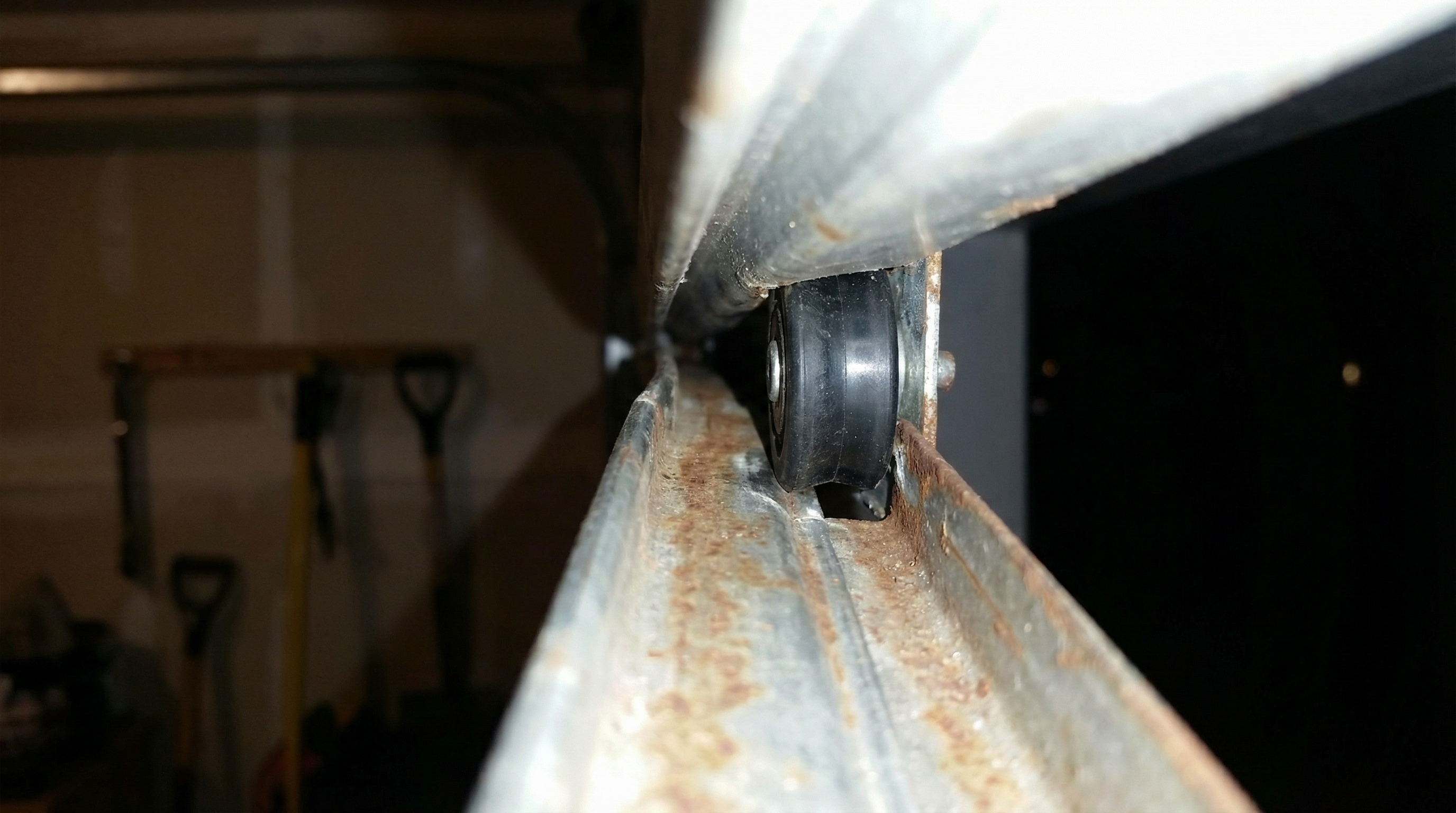 close-up view of misaligned garage door track with visible gap between roller and track