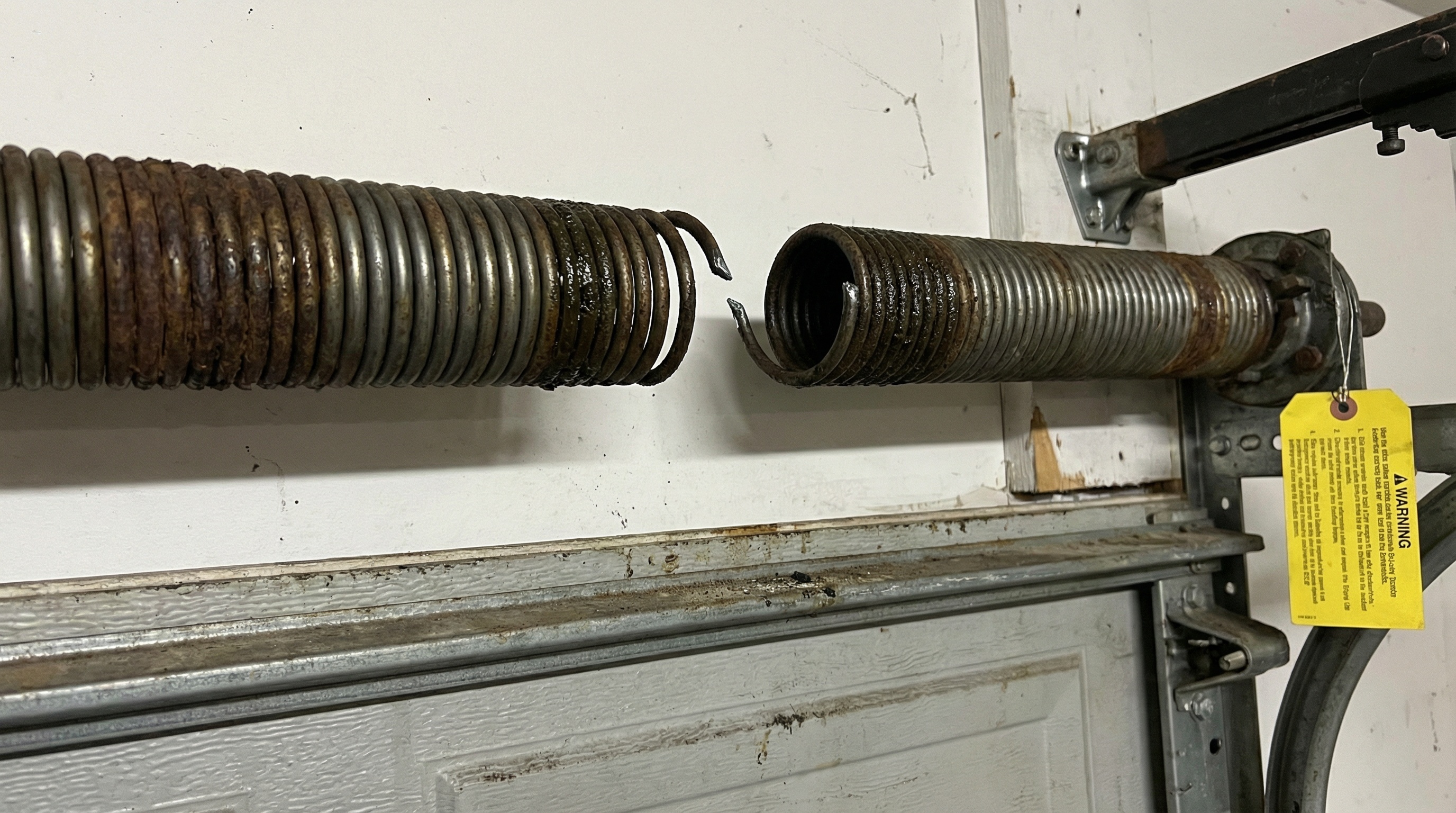 Broken garage door spring damage example showing safety hazard