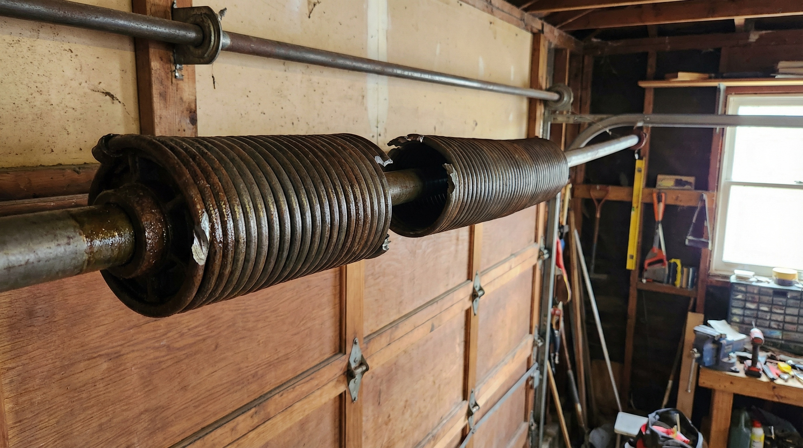 Close-up view of garage door spring with visible gap and break in coil
