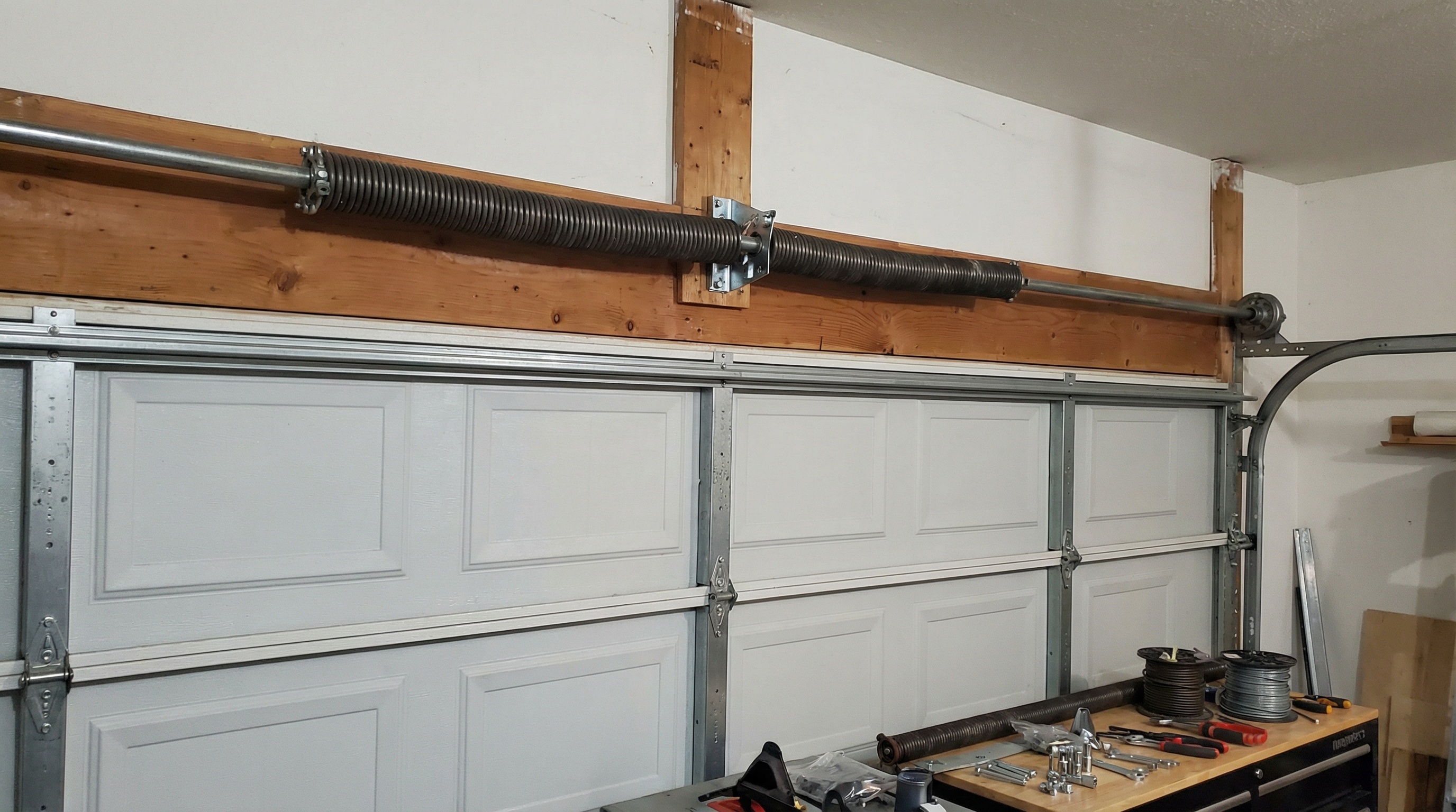 Torsion spring installation mounted horizontally above garage door opening on metal shaft