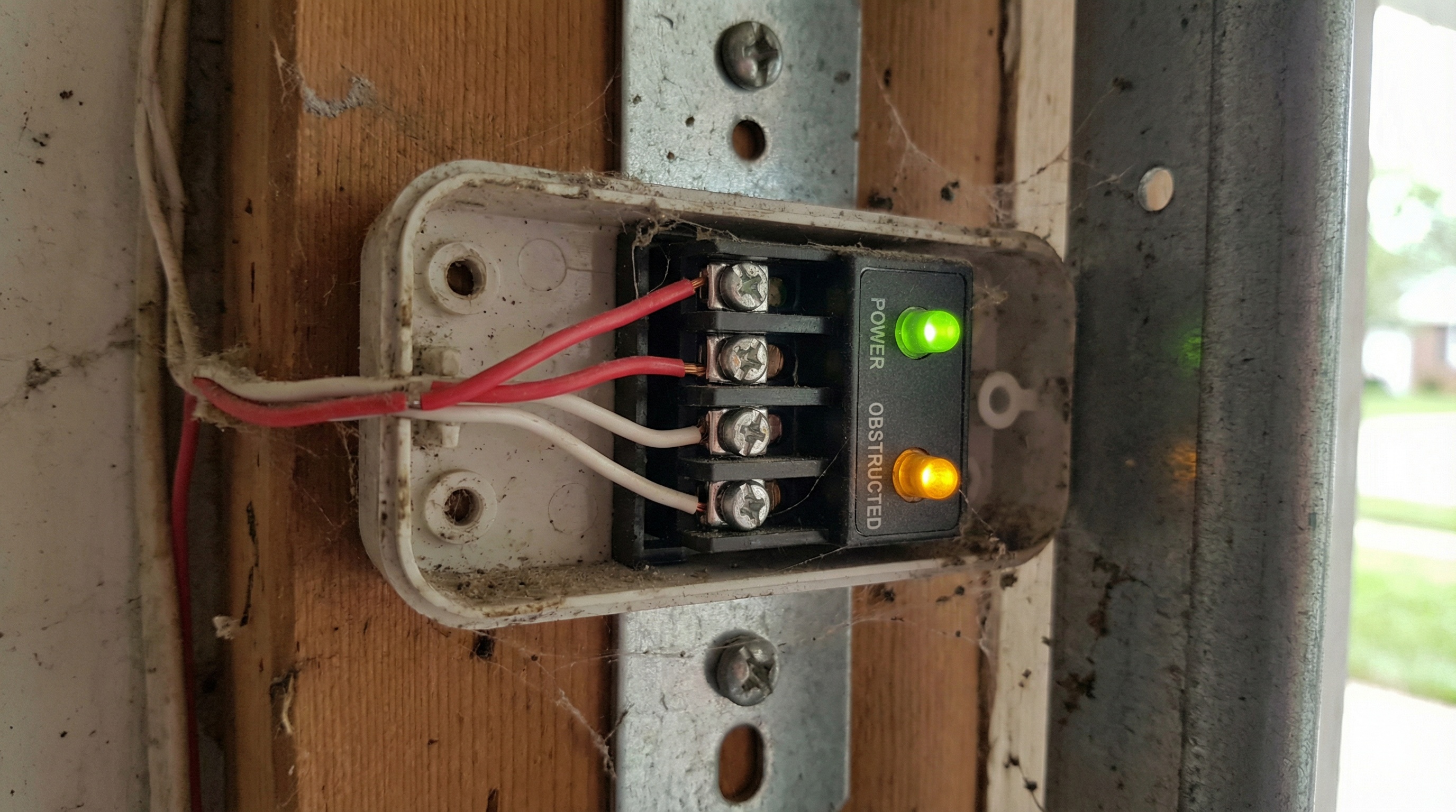 Close-up view of garage door sensor wiring connections and LED status lights